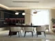A modern luxury dining room featuring white sculptural chairs with curved silhouettes, a dark minimalist table, and a futuristic organic pendant light against a backdrop of dark kitchen cabinetry.