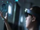 A person wearing an advanced AR headset interacting with a glowing, holographic digital globe suspended above their hand, representing the future of interactive live dealer technology.