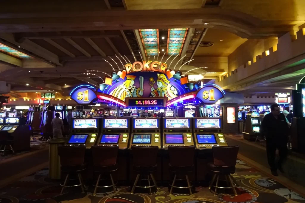 A row of five Game King video poker slot machines in a dimly lit casino, featuring a large illuminated "POKER" sign with playing card king and queen graphics and a $4,186.25 jackpot display.
