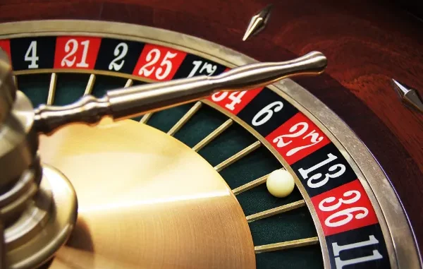 Close-up of a high-end gold and wood roulette wheel with a white ball landing on a black number.