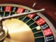 Close-up of a high-end gold and wood roulette wheel with a white ball landing on a black number.