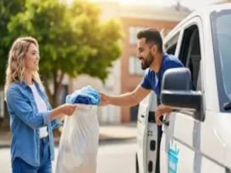 A smiling woman handing a white bag of laundry to a delivery professional in a white van on a sunny street.