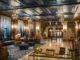 A luxurious hotel lobby featuring wood-paneled walls, blue coffered ceilings, ornate chandeliers, and a grand staircase decorated for the holidays.