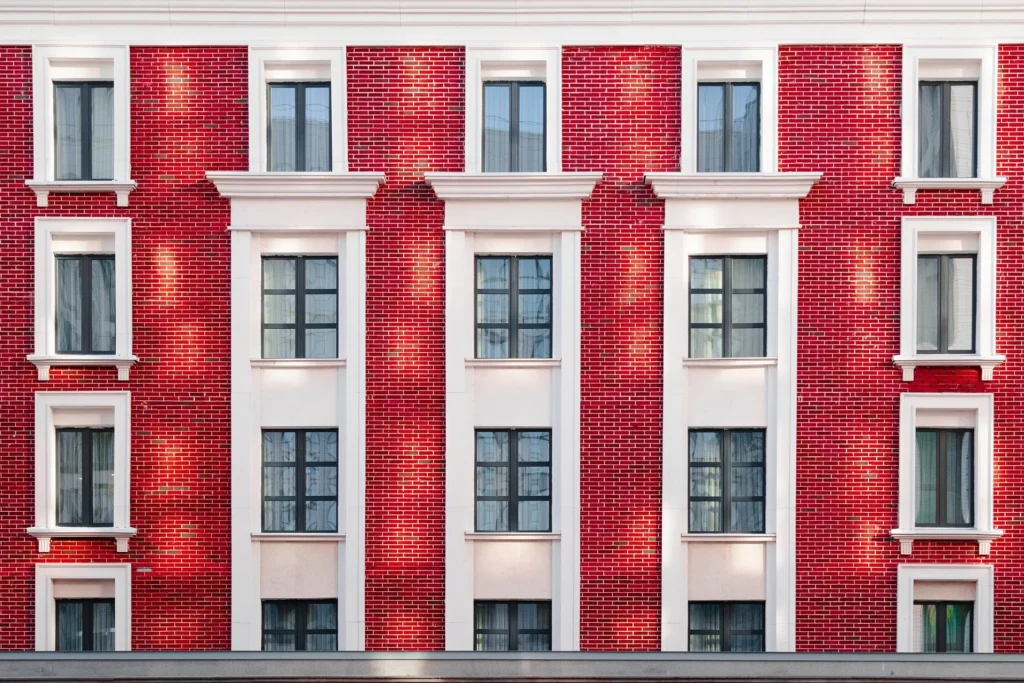 Close-up view of a vibrant red brick building facade with white window trim, illustrating the importance of proper water drainage systems to protect structural integrity.