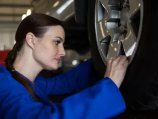 A white Tesla Model 3 on a professional laser wheel alignment rack in a service center.