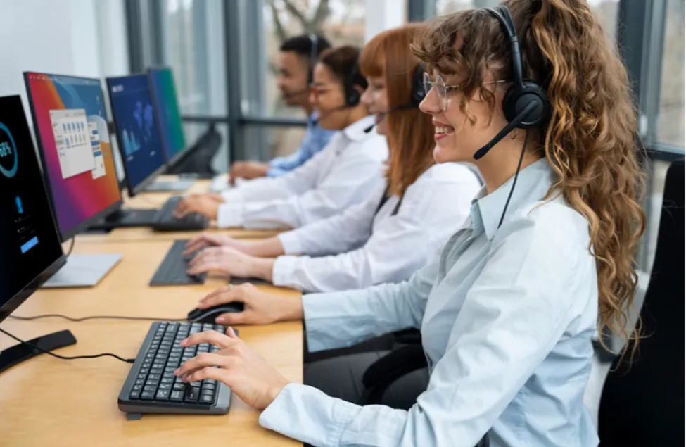 A diverse team of professional customer support agents wearing headsets and working at modern computer stations in a high-tech inbound call center environment.