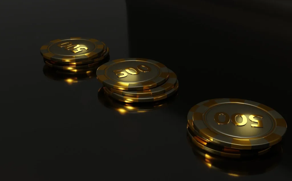 Three stacks of premium gold and black 500-denomination gaming chips resting on a reflective dark surface, symbolizing the high-standard betting and offshore gaming industry in Anjouan.