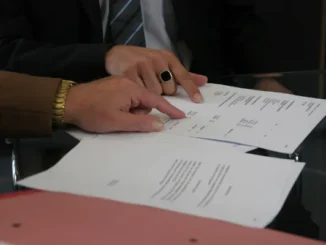 Close-up of a bankruptcy attorney pointing to financial documents while explaining asset protection strategies to a client.