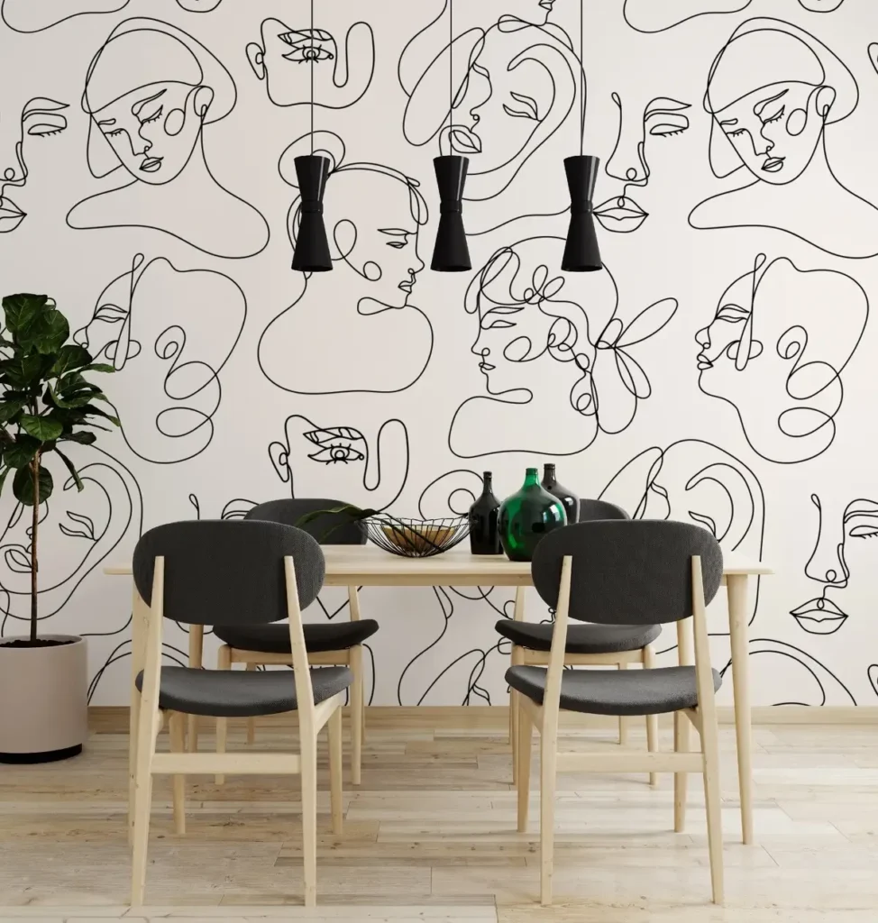 Minimalist black and white face-patterned wallpaper behind a light wood dining set.