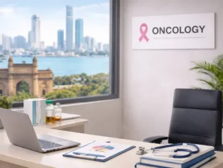 A professional oncology consultation room featuring a desk with a stethoscope and medical charts, with a pink breast cancer awareness ribbon visible on the wall.