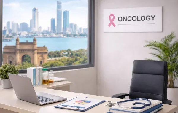A professional oncology consultation room featuring a desk with a stethoscope and medical charts, with a pink breast cancer awareness ribbon visible on the wall.