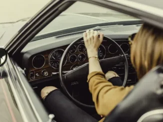 Interior view of a driver's perspective in a classic car, showing proper hand placement on the steering wheel and seated posture to prevent back pain during daily travel.