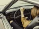 Interior view of a driver's perspective in a classic car, showing proper hand placement on the steering wheel and seated posture to prevent back pain during daily travel.