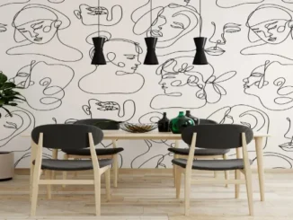 A modern dining room featuring a bold black and white wallpaper with continuous line art of abstract faces, paired with light wood furniture and black pendant lights.