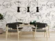 A modern dining room featuring a bold black and white wallpaper with continuous line art of abstract faces, paired with light wood furniture and black pendant lights.