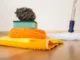 A stack of colorful cleaning supplies including a steel wool pad, sponges, and microfiber cloths on a hardwood floor for move-out cleaning in Chicago.