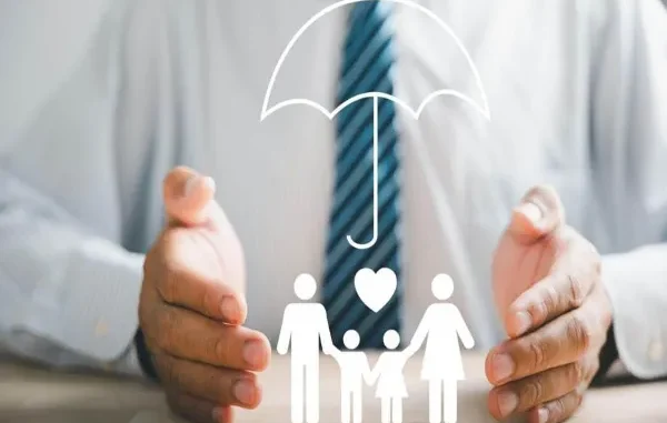 A conceptual image showing a person’s hands shielding a family icon under an umbrella, representing protection and medical insurance coverage.