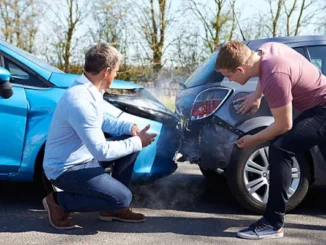 Two men inspecting the front and rear bumper damage of a blue car and a grey car after a road accident.