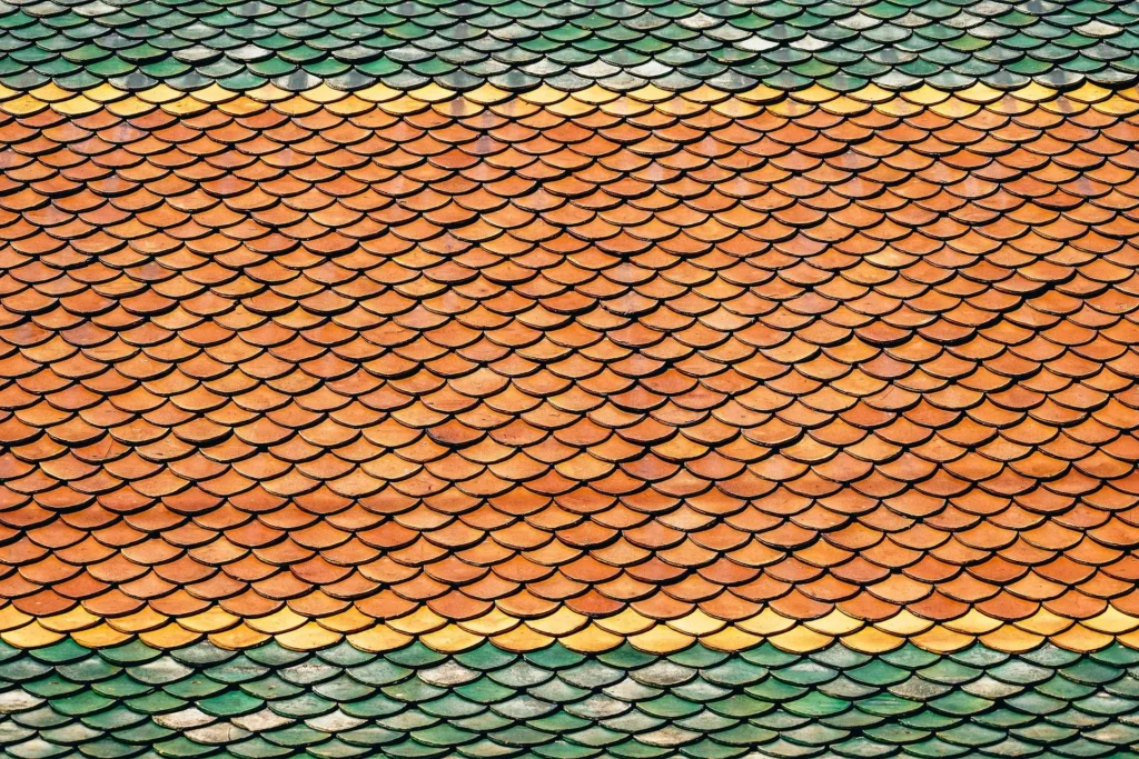 Detailed close-up of colorful orange, yellow, and green scalloped roof tiles, illustrating the variety of materials a professional roofing company in Austin can install or repair.