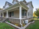Exterior of a Charlotte home featuring a wrap-around porch, brick foundation, and a clean white gutter system with downspout extensions to prevent water damage.
