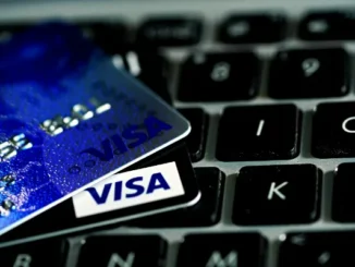 Two Visa credit cards resting on a black laptop keyboard, illustrating secure online checkout and 3DS 2.0 authentication.