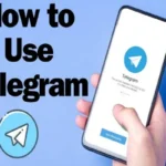 A hand holding a smartphone displaying the Telegram welcome screen with the blue paper plane logo and "Start Messaging" button against a blue background.