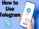 A hand holding a smartphone displaying the Telegram welcome screen with the blue paper plane logo and "Start Messaging" button against a blue background.