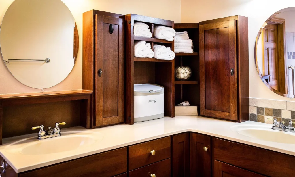 A meticulously organized and sanitized dual-sink bathroom vanity with dark wood cabinetry, white countertops, and rolled fresh towels, demonstrating the high level of hygiene achieved through professional deep cleaning.