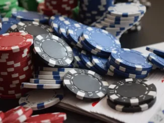 High-angle shot of stacked red, blue, and black casino chips on a table next to a deck of playing cards, representing strategic betting.