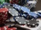 High-angle shot of stacked red, blue, and black casino chips on a table next to a deck of playing cards, representing strategic betting.