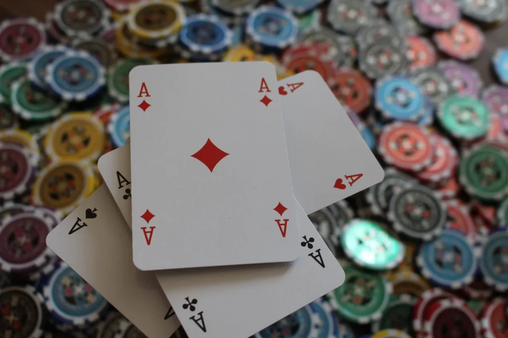 A winning poker hand featuring four aces spread over a large pile of colorful casino gambling chips, illustrating effective casino strategies for consistent wins.