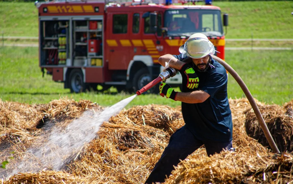 Firefighter Directing Water Stream onto Dry Vegetation