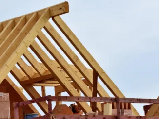Close-up of a wooden roof truss system and rafters on a new residential construction site against a clear sky.