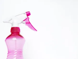 A close-up of a pink translucent spray bottle with a white and pink trigger nozzle against a clean white background.