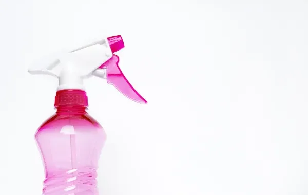 A close-up of a pink translucent spray bottle with a white and pink trigger nozzle against a clean white background.