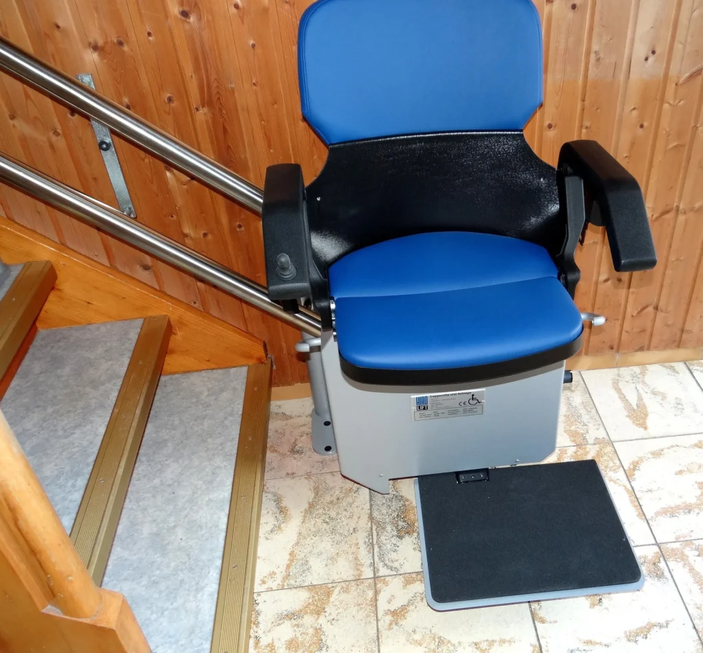 A modern blue and black motorized stair lift installed on a wooden staircase with a silver dual-rail system.