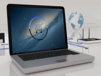 A 3D rendering of an open laptop featuring a glowing blue shopping cart icon inside a circle on the screen, set against a background with a globe and networking equipment to represent global digital commerce.