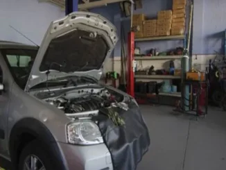 A silver BMW 3 Series with its hood open undergoing engine diagnostics and performance repair inside a professional automotive workshop.