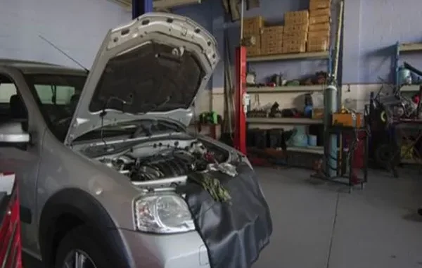 A silver BMW 3 Series with its hood open undergoing engine diagnostics and performance repair inside a professional automotive workshop.