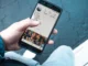 A person holding a smartphone displaying an Instagram profile page with follower counts and a photo grid, used to represent social media management and growth.