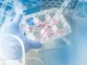 A gloved hand holds a multi-well cell culture plate while a serological pipette dispenses pink liquid into one of the wells in a laboratory hood.