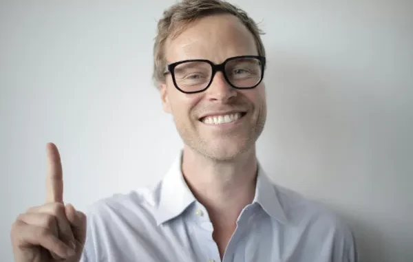 A smiling man with glasses pointing his index finger up, representing a smart betting strategy tip for casino players and punters.