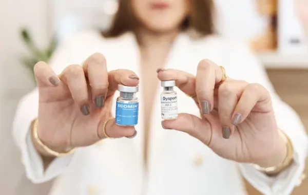A practitioner holding two small medication vials, Xeomin and Dysport, illustrating the choice between SubQ and IM injection routes for peptide therapy.