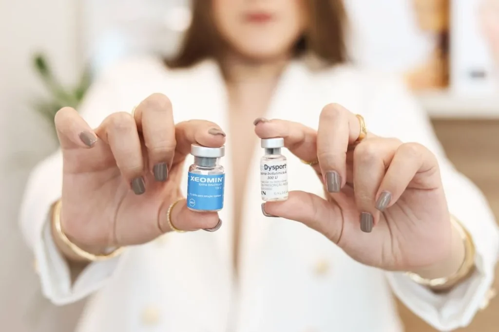 A healthcare professional holding two small medical vials, Xeomin and Dysport, side-by-side, representing the choice between subcutaneous (SubQ) and intramuscular (IM) injection routes for a peptide stack.