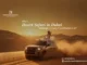 A woman in a white dress sitting on top of a 4x4 SUV during a dune bashing desert safari in Dubai at golden hour.