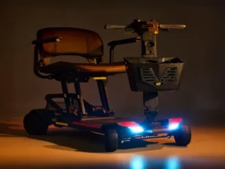 Black Golden folding mobility scooter featuring illuminated LED headlights, armrests, and a front storage basket.