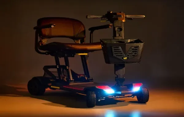 Black Golden folding mobility scooter featuring illuminated LED headlights, armrests, and a front storage basket.