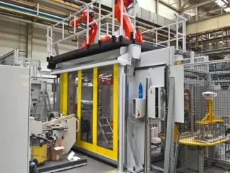 High-speed machine protection door with yellow borders and clear windows safeguarding an automated robotic work cell in an industrial manufacturing plant.
