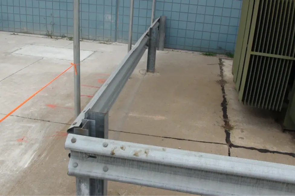 Close-up of a galvanized steel W-beam highway guardrail installed on a concrete surface, demonstrating the sturdy crash barrier infrastructure used to reduce traffic accident severity.