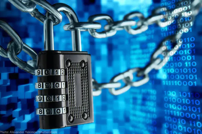 A heavy, metallic combination padlock secured with chains, set against a dark blue background glowing with streams of binary code and digital data.